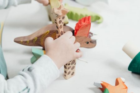 child holding brown and green wooden animal toys